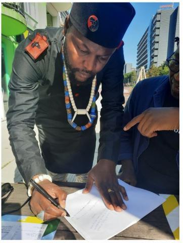 Mwazulu signeert het manifest van de UDC, een gift voor voor AFRO Magazine